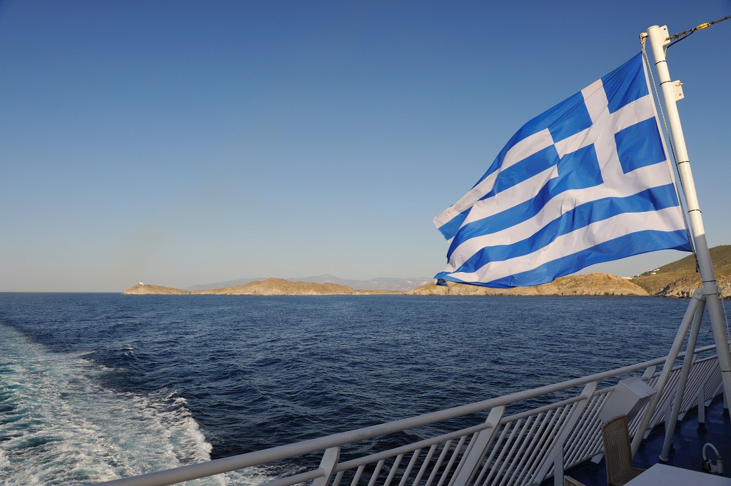 Kykladen-062009-006.jpg - Munter flattert die griechische Flagge im Wind während die Kykladeninseln bei bestem an uns gemächlich vorbeiziehen.